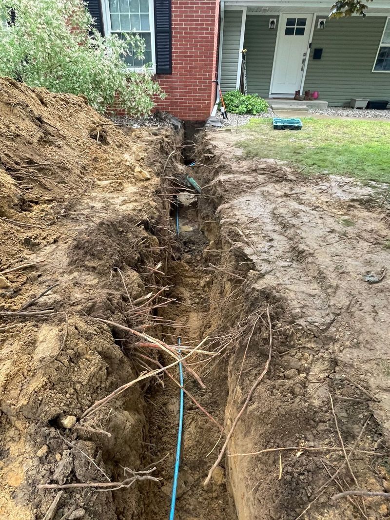 A large hole in the ground in front of a house.