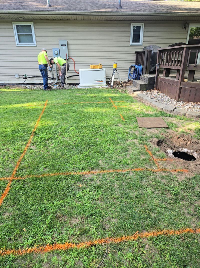 A group of men are working in a yard in front of a house.