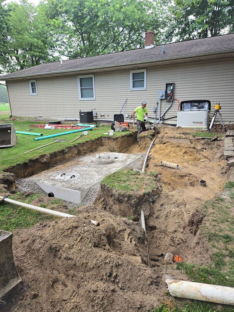 A man is digging a hole in the dirt in front of a house.