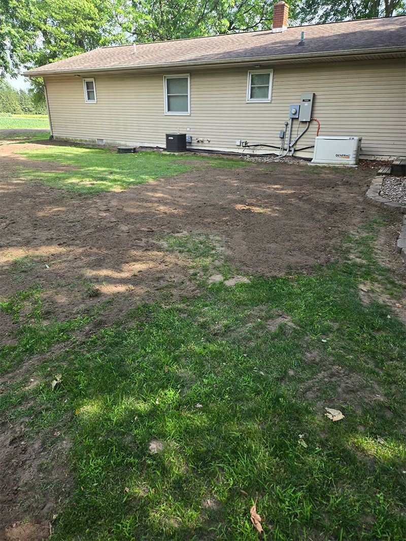 A house with a lot of grass and dirt in front of it.