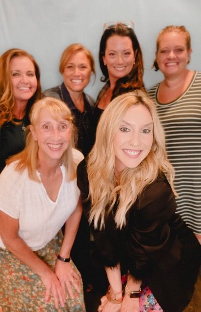A group of women are posing for a picture and smiling for the camera.