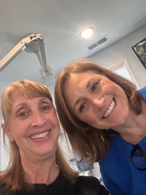 Two women are posing for a picture and smiling for the camera.