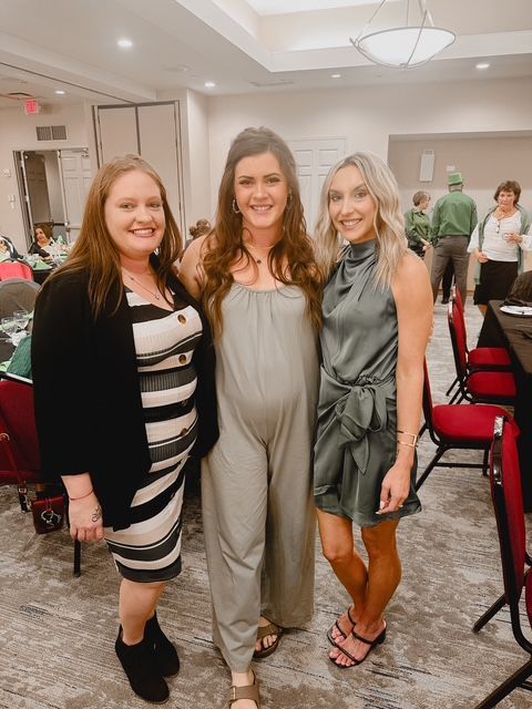 Three women are posing for a picture together in a room.