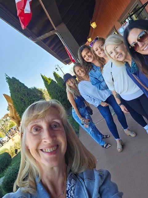 A group of women are posing for a selfie in front of a building.