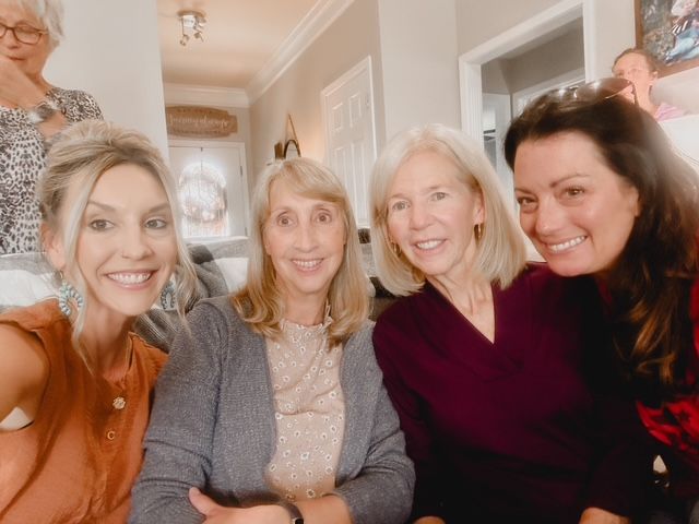 Four women are posing for a picture together in a room.