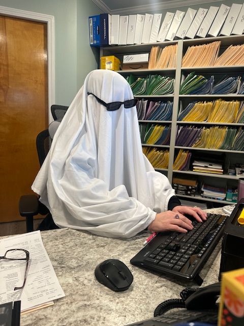 A person in a ghost costume is typing on a keyboard.