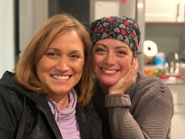 Two women are posing for a picture and one is wearing a headband with hearts on it.