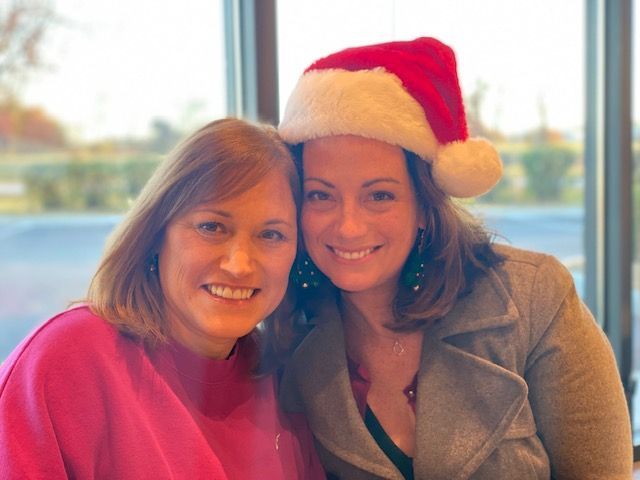 Two women, one wearing a festive Santa hat, strike a pose for the camera.
