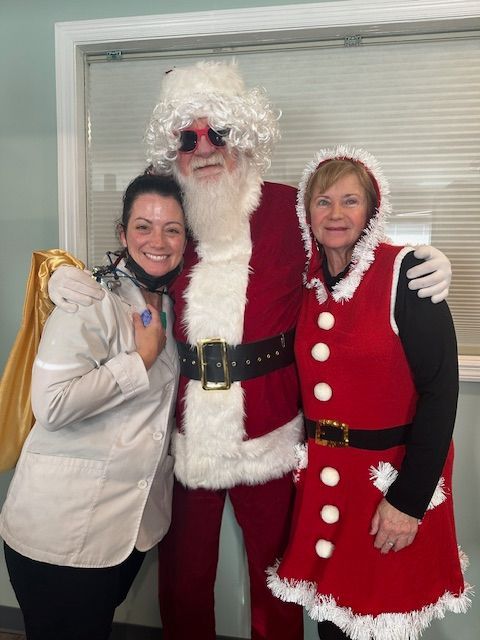 Two women pose with Santa Claus.