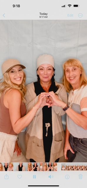 Three women smiling and making a heart shape with their hands.