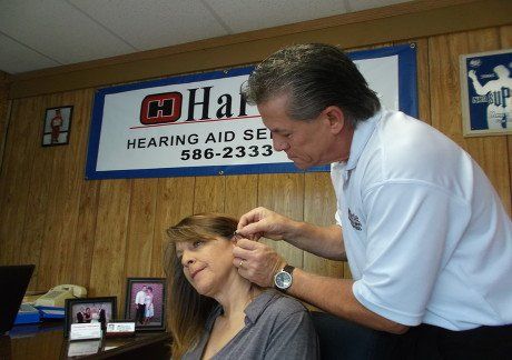 Mr. Hartley placing a hearing aid to a patient