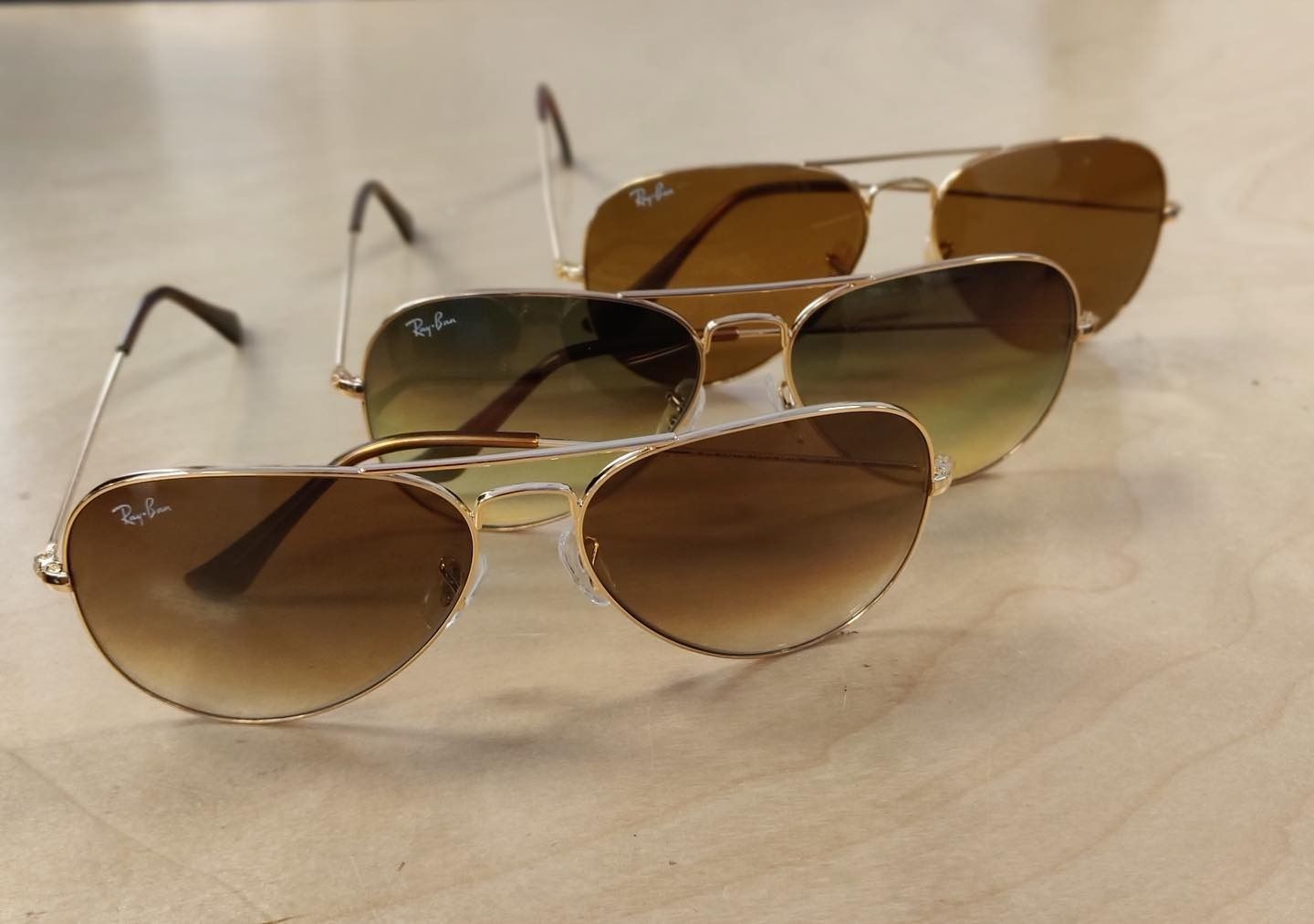 Three ray-ban sunglasses are lined up on a table