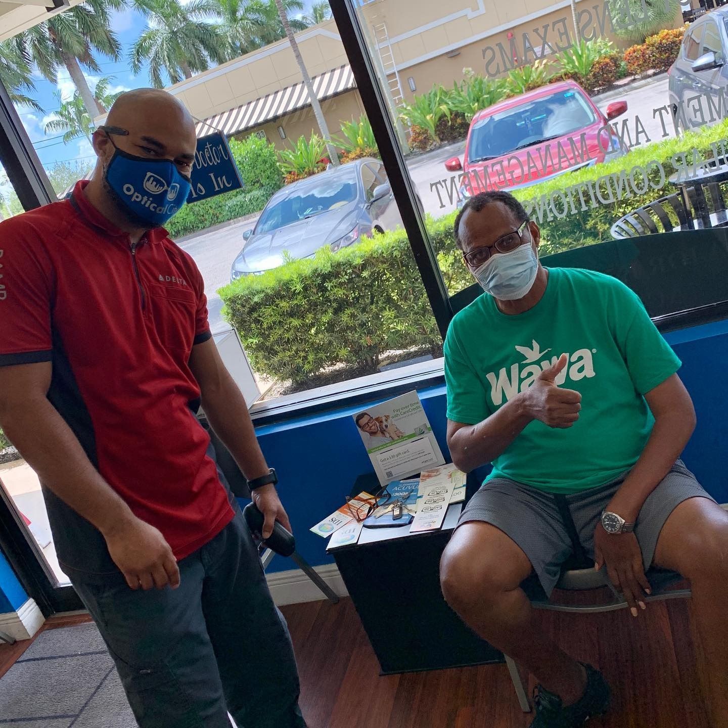 Two men wearing face masks are standing next to each other in a room.