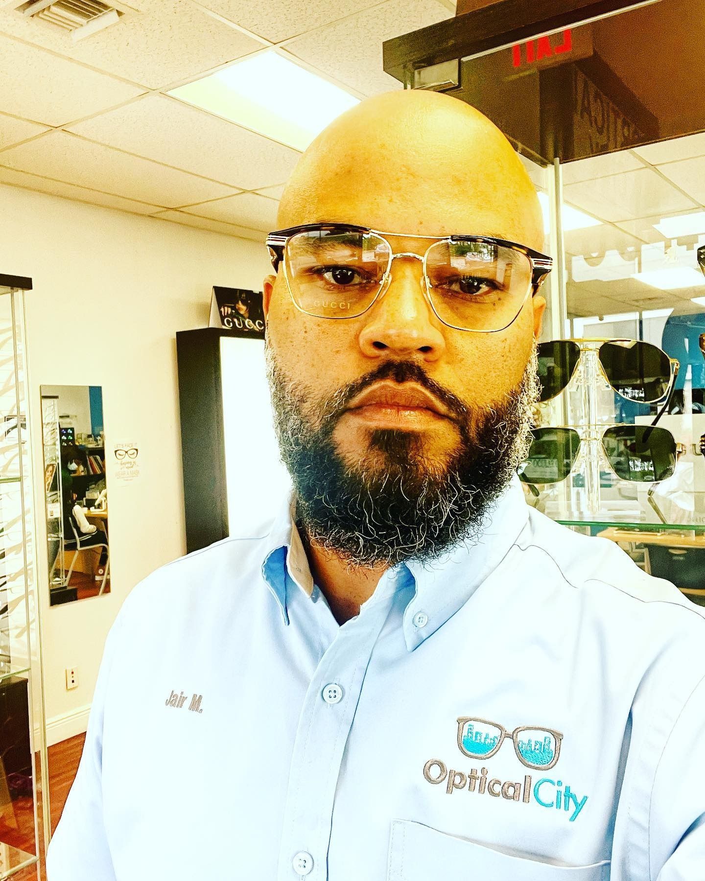A man wearing glasses and a shirt that says optical city