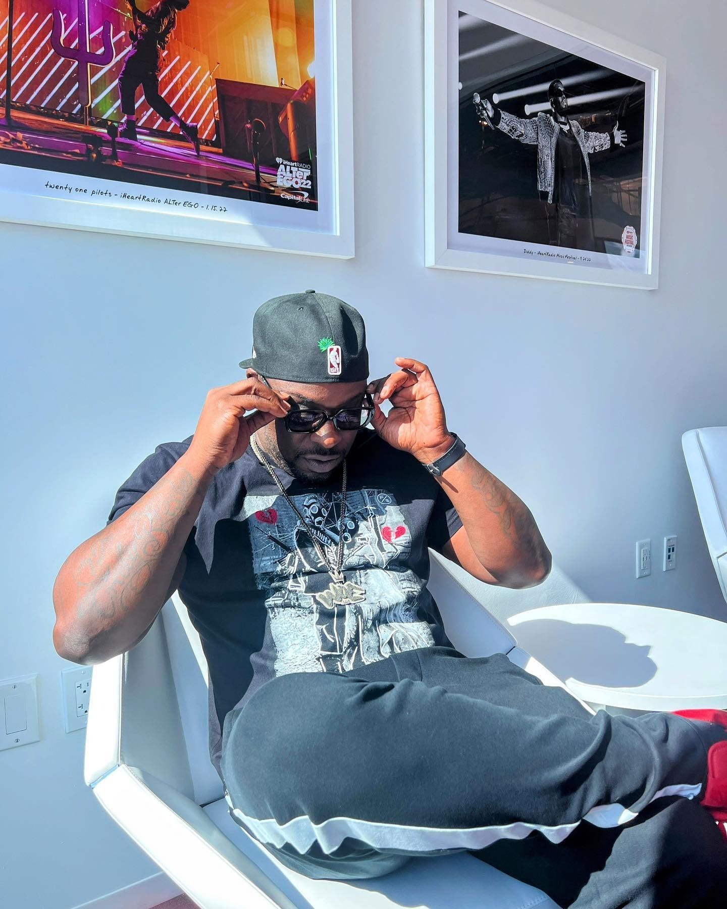 A man wearing a hat and sunglasses is sitting in a chair.