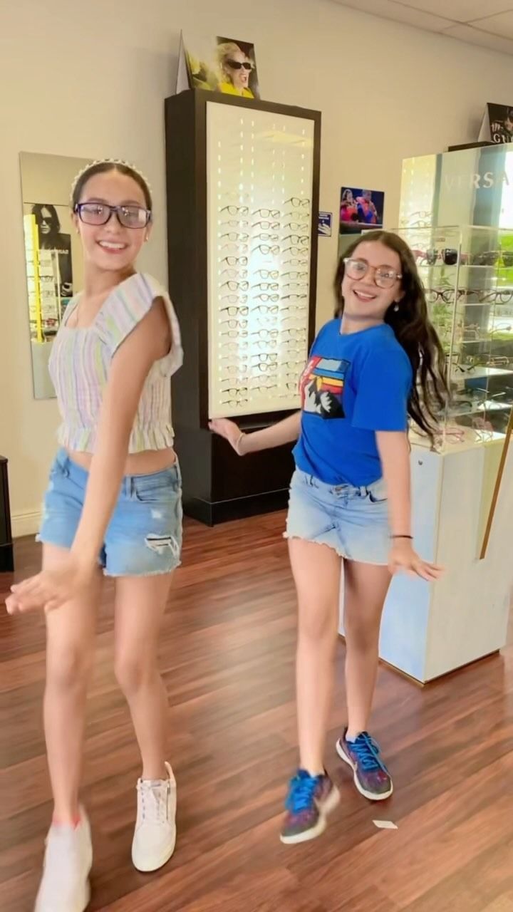 Two young girls are standing next to each other in an optical store.