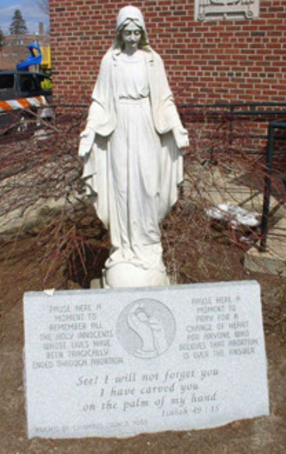 A statue of a woman standing next to a plaque that says 