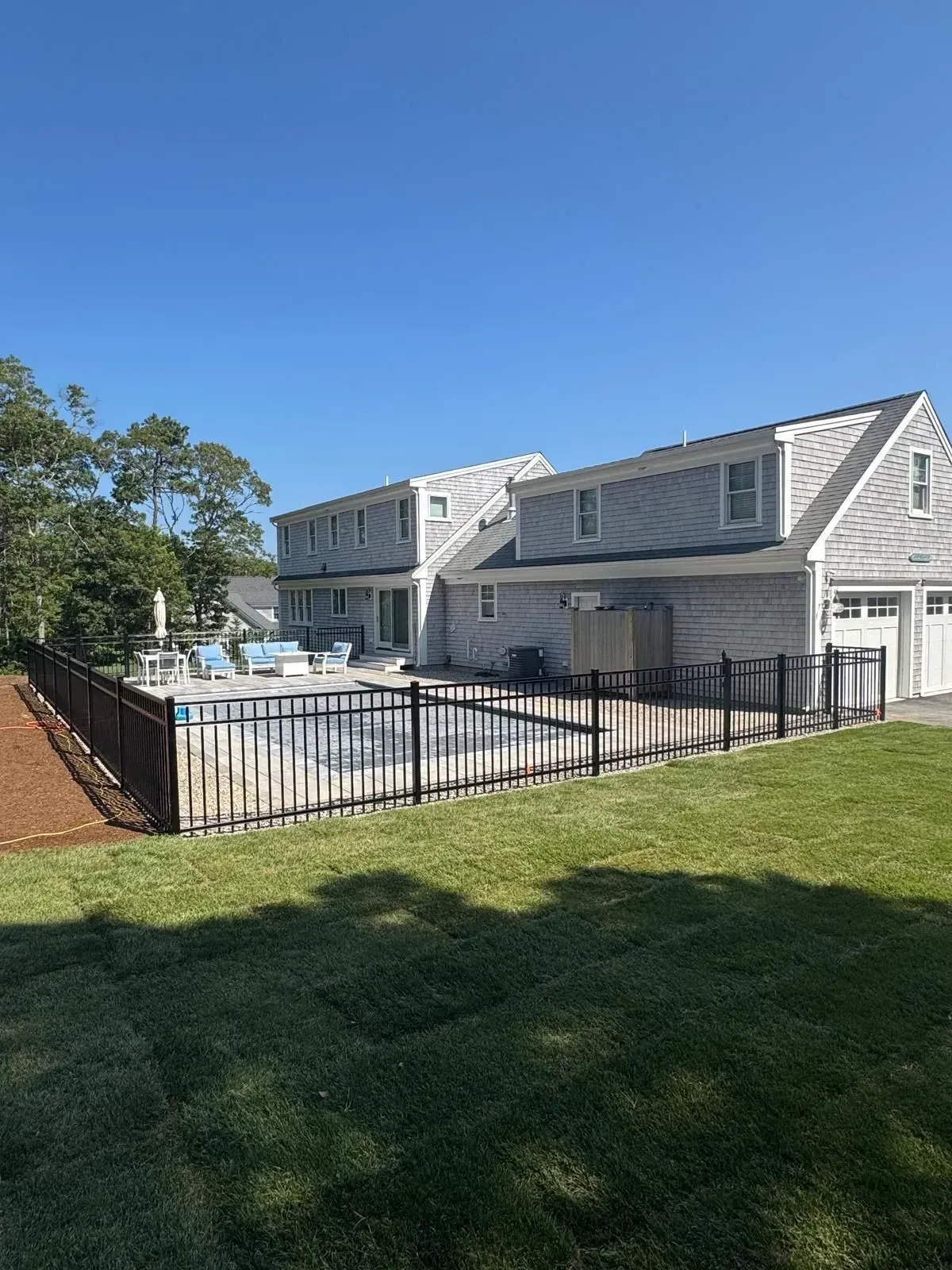 Apartment building with fenced swimming pool on a sunny day.