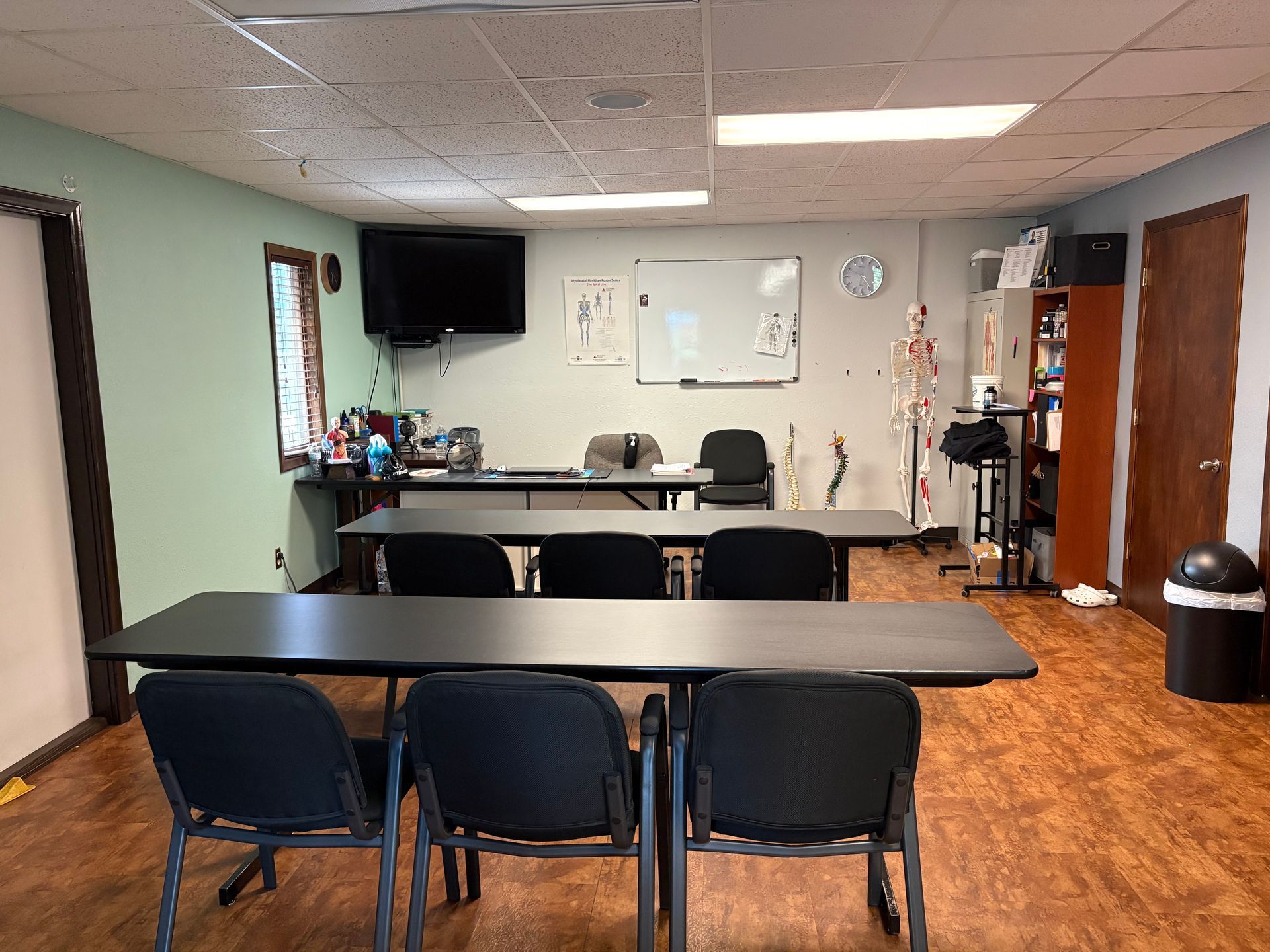 Meeting room with tables, chairs, a wall-mounted TV, and a whiteboard on the far wall