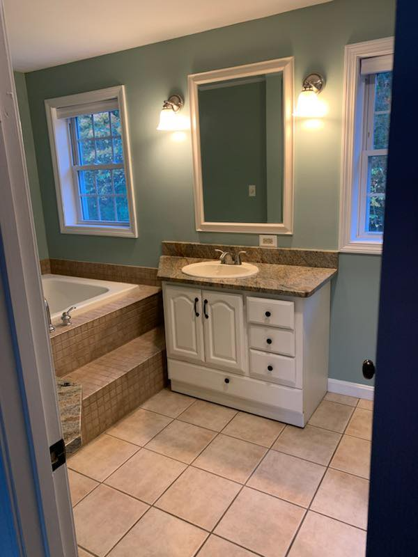 A bathroom with a tub , sink and mirror