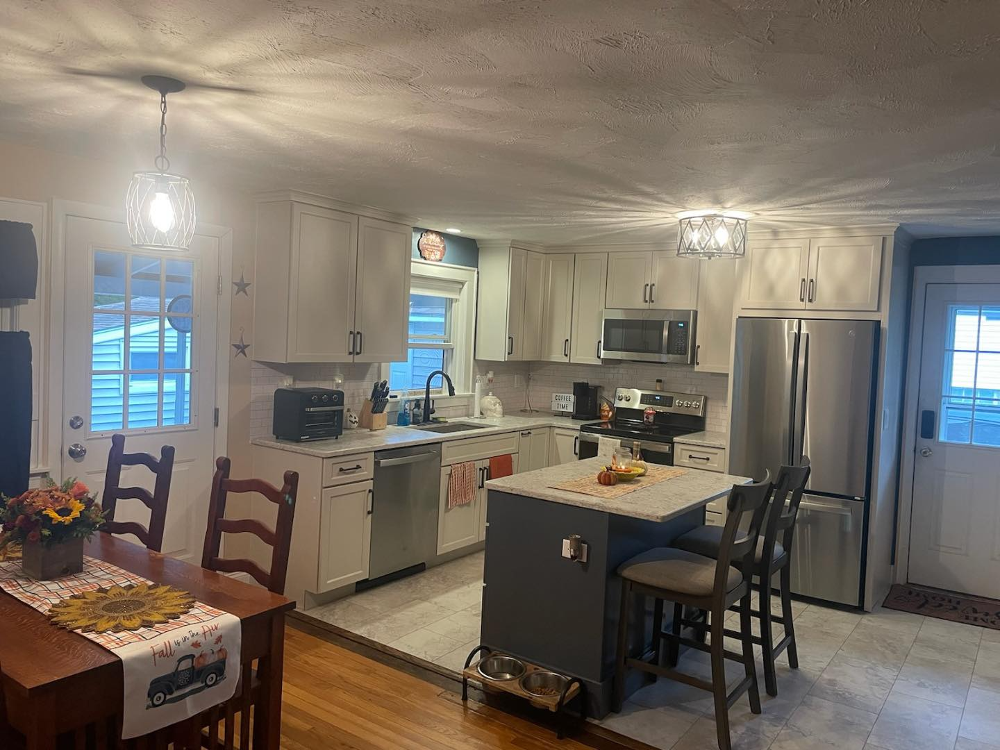 A kitchen with white cabinets , stainless steel appliances , a table and chairs.