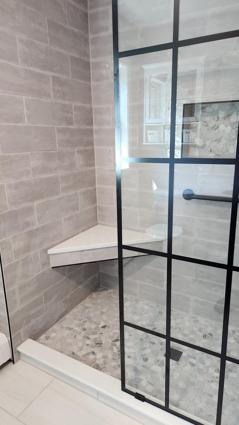 A bathroom with a walk in shower and a glass door.
