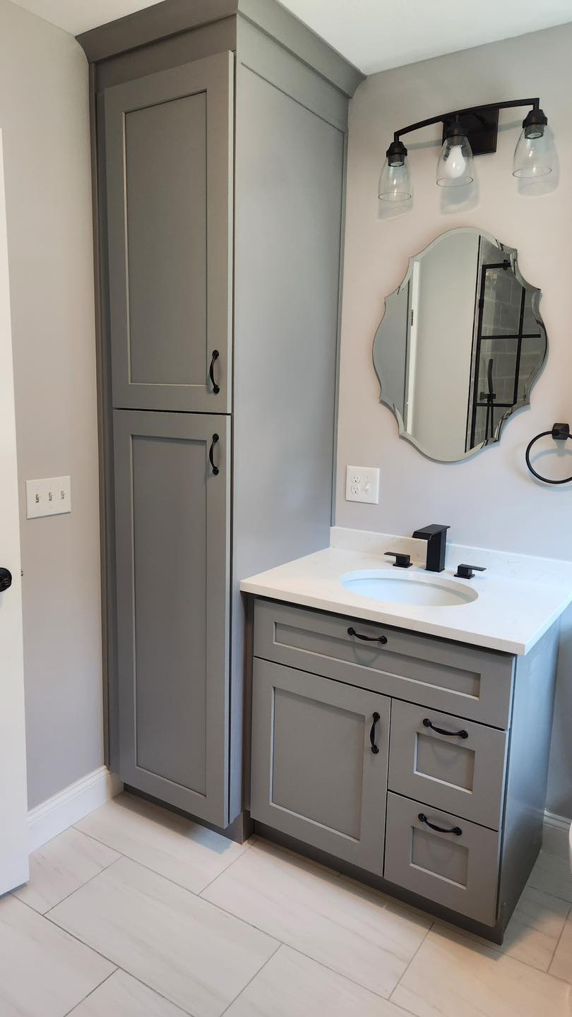 A bathroom with gray cabinets , a sink , and a mirror.