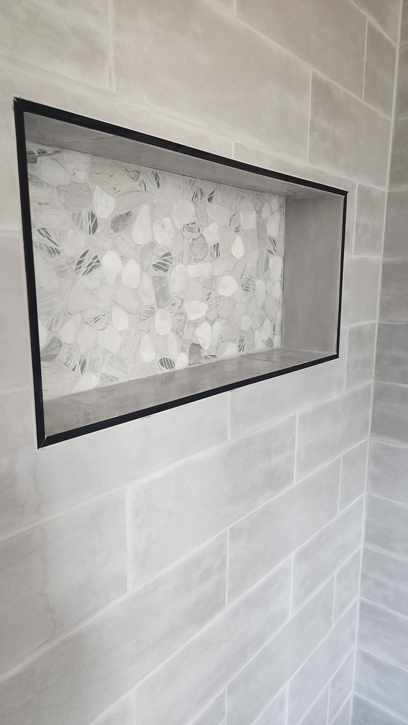 A shower niche with marble tiles in a bathroom.