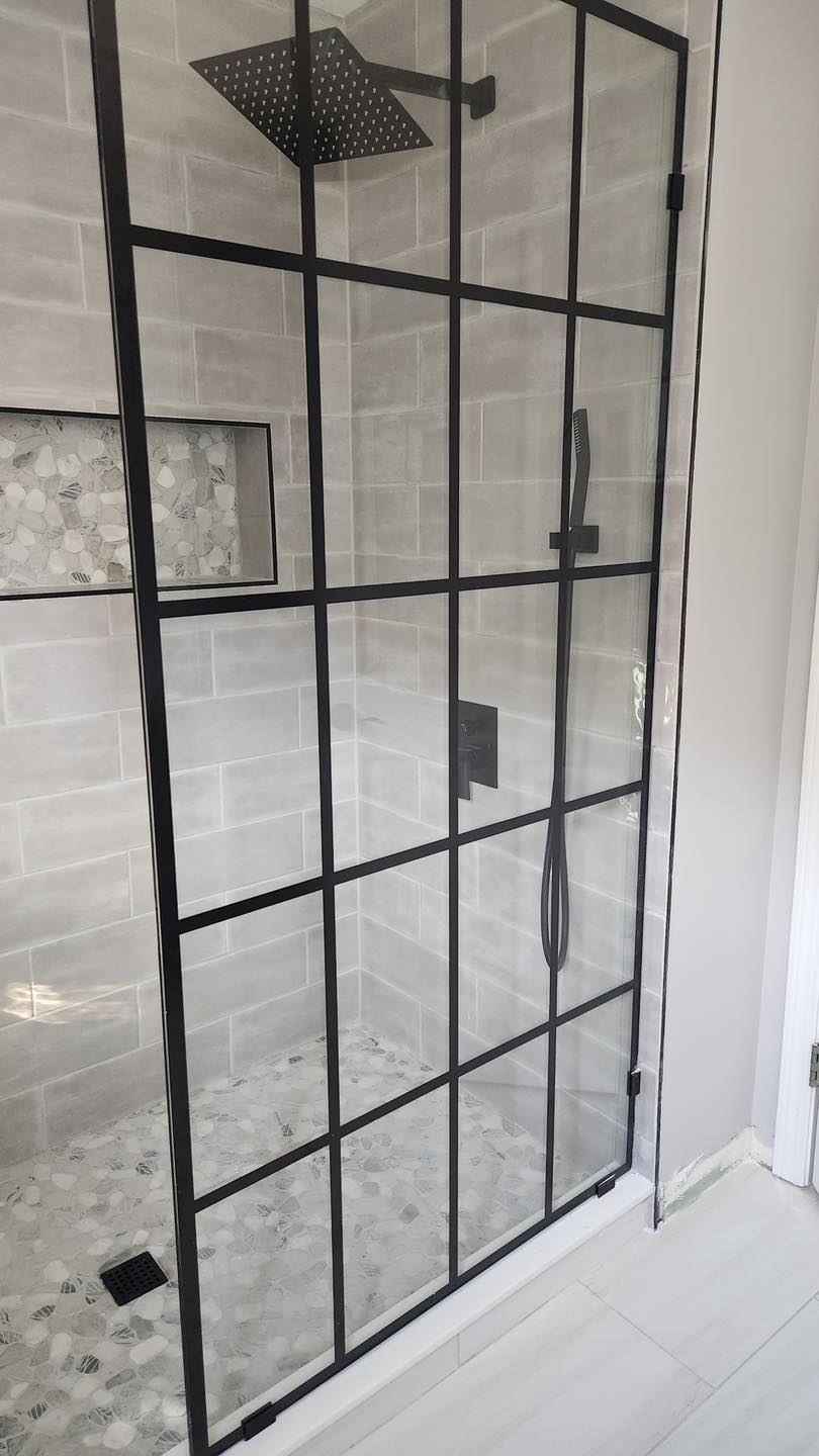 A shower stall with a black frame and a shower head.