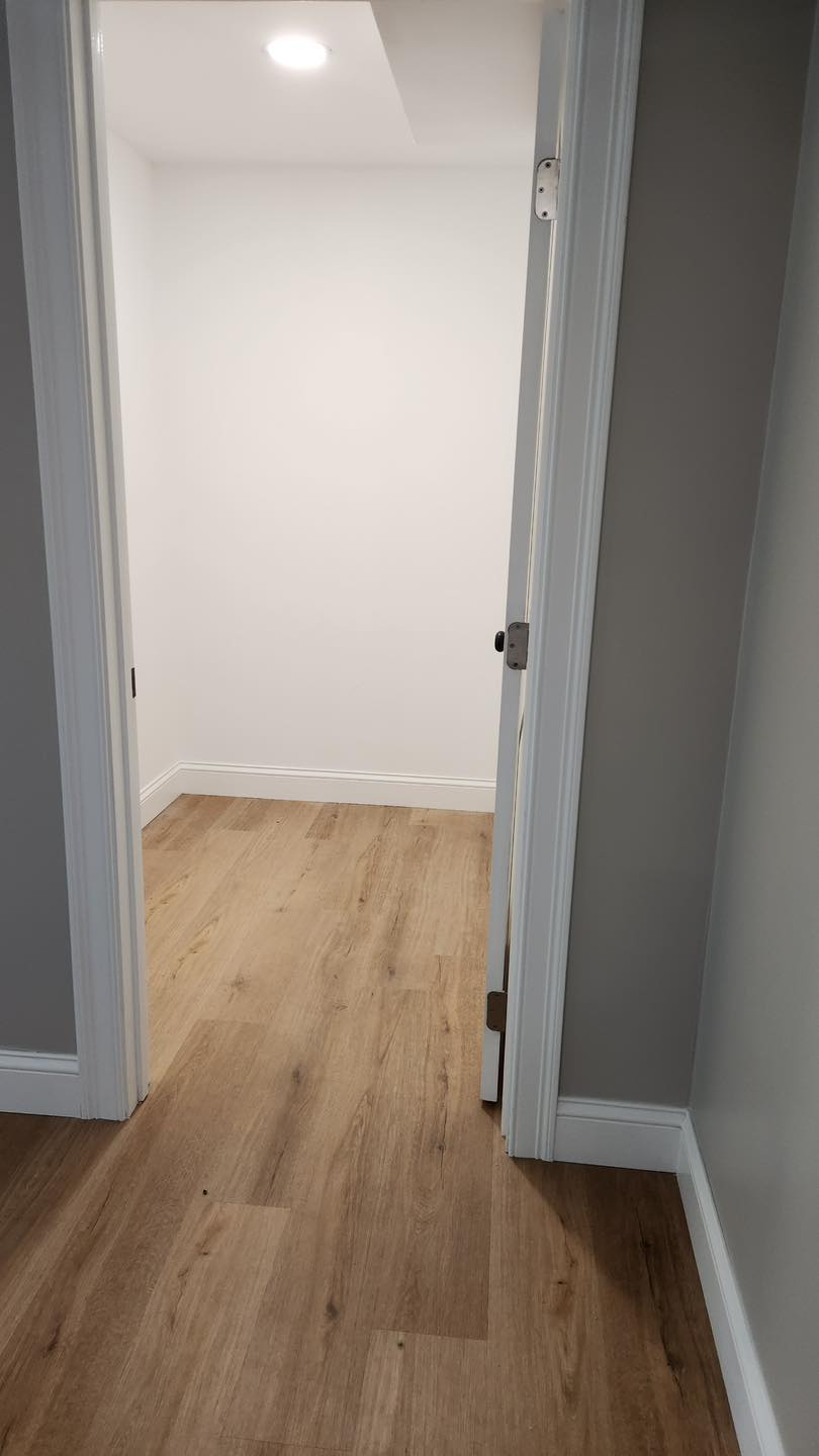 A hallway in a house with hardwood floors and white walls.