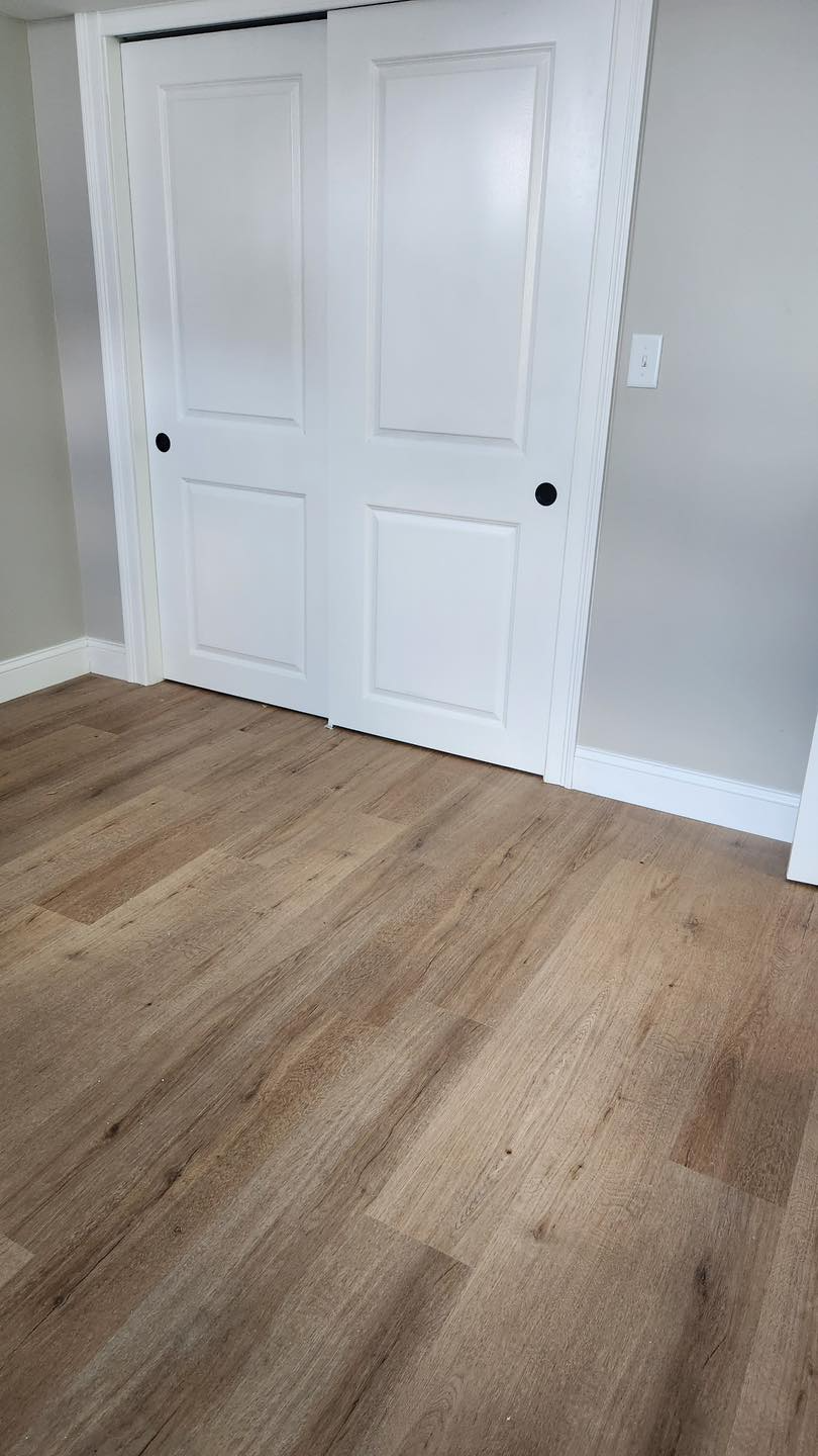 A bedroom with hardwood floors and white doors.