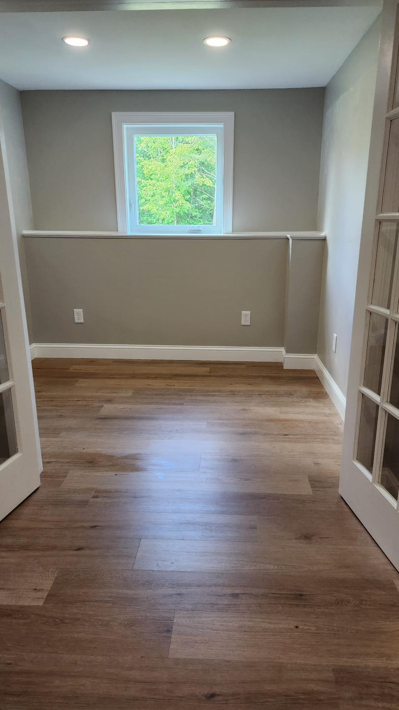 An empty room with hardwood floors and a window.