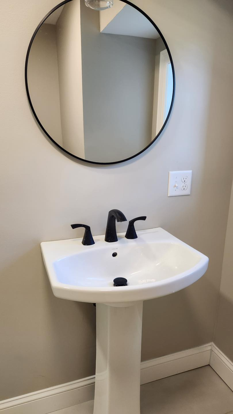 A bathroom sink with a round mirror above it.