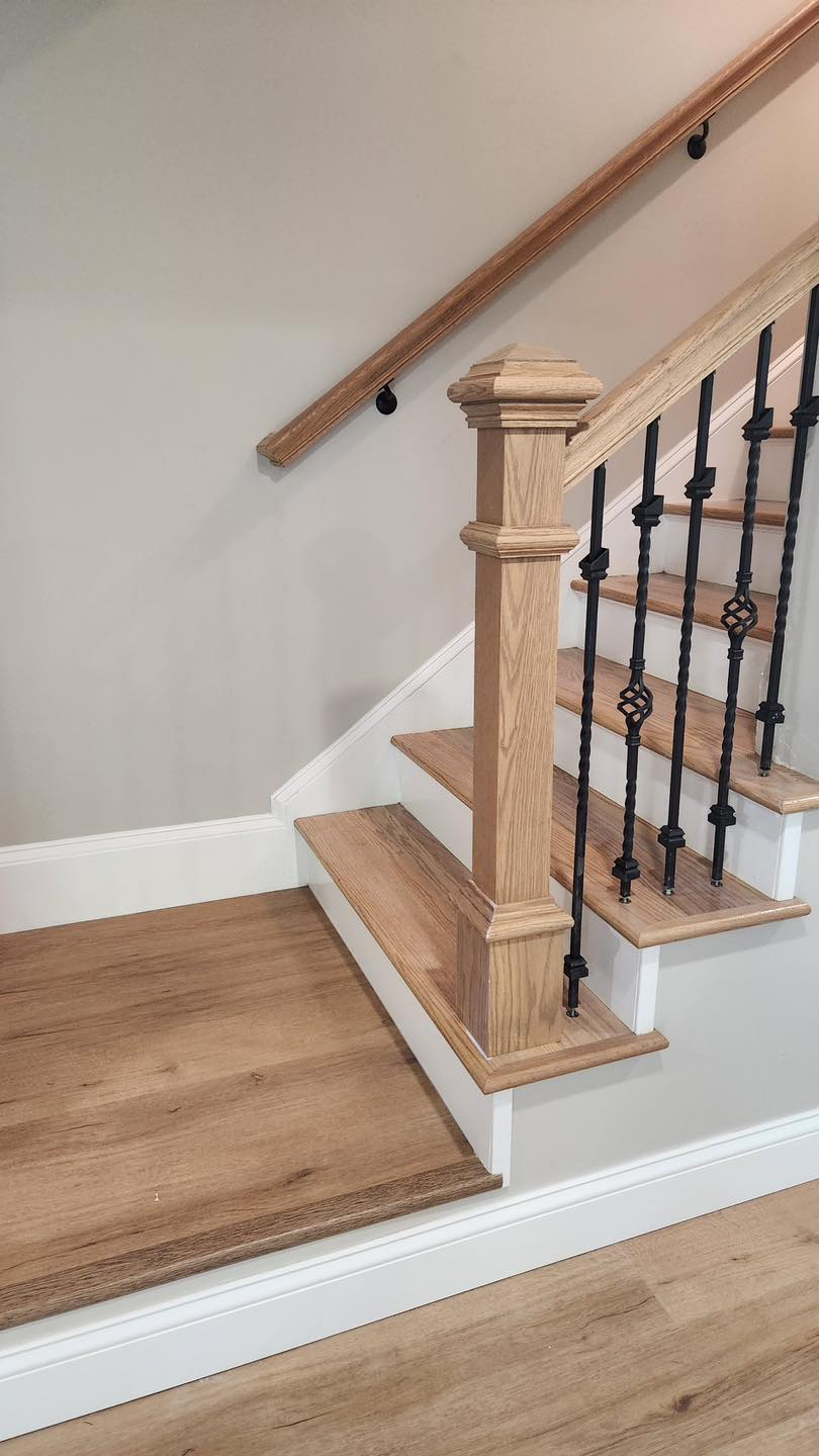 A wooden staircase with a wrought iron railing and a wooden handrail.