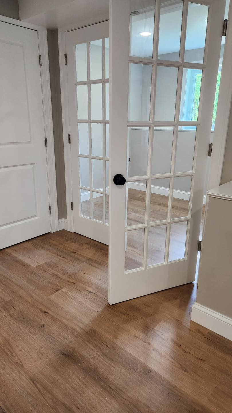 A room with hardwood floors and white french doors.
