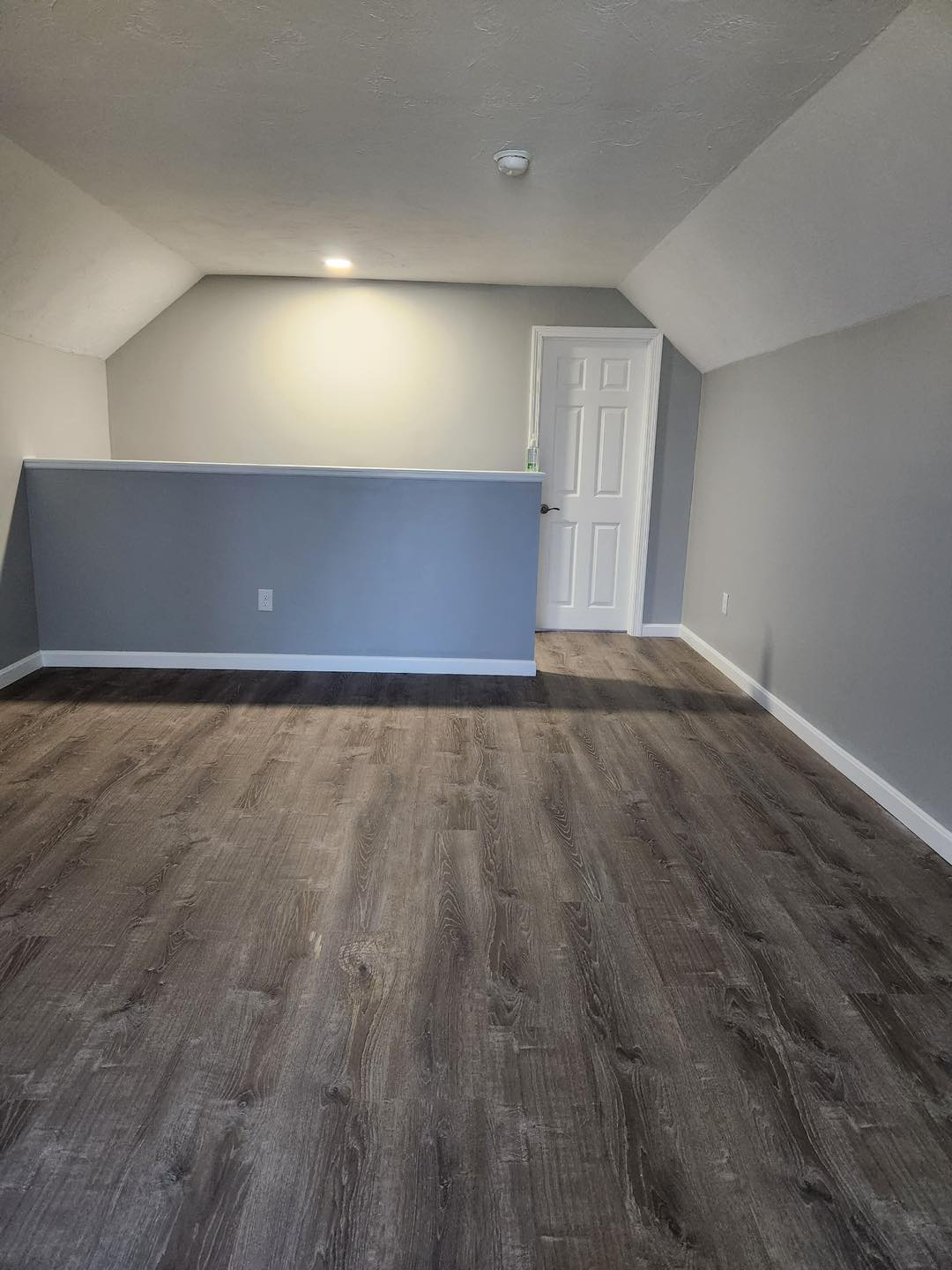 An empty room with a wooden floor and gray walls.