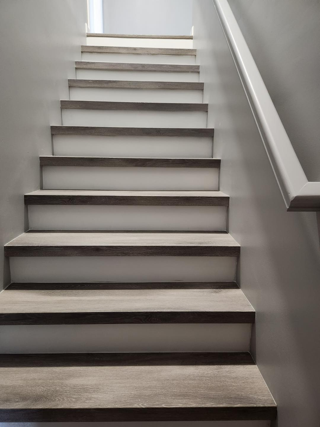 A staircase with a white railing leading up to a light.