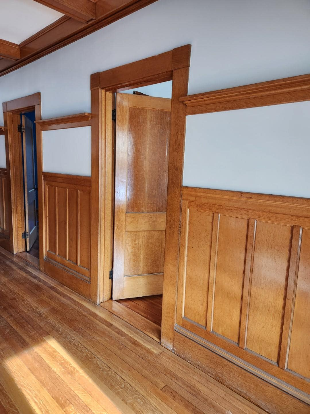 A hallway with wood paneling and a door that is open.