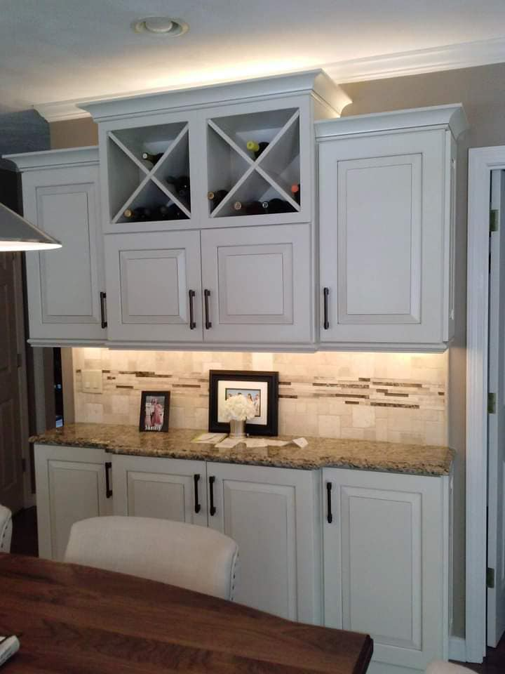A kitchen with white cabinets and a wooden table and chairs.
