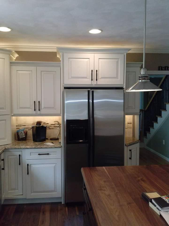 A kitchen with white cabinets and a stainless steel refrigerator