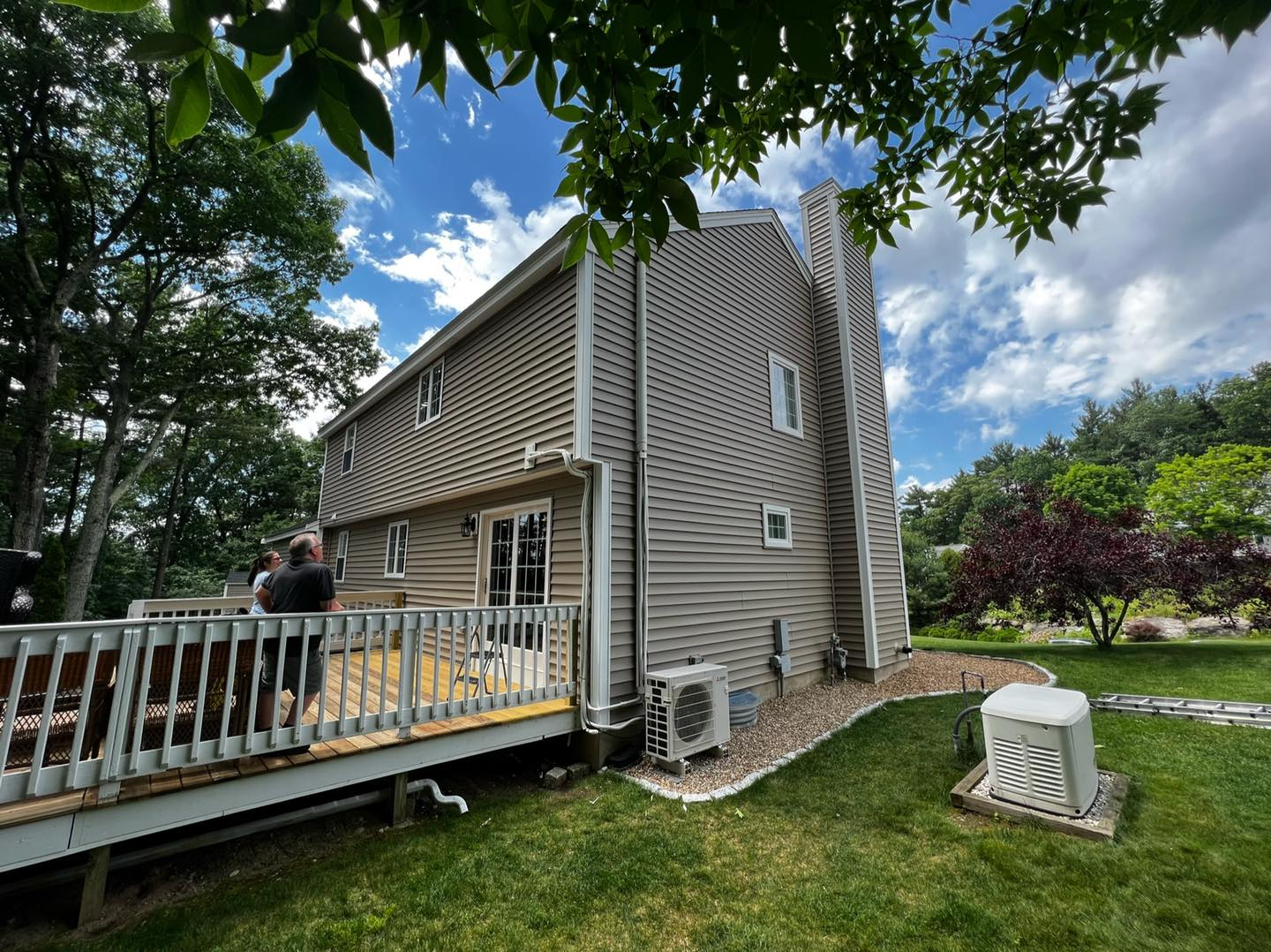 A man is standing on a deck next to a house.