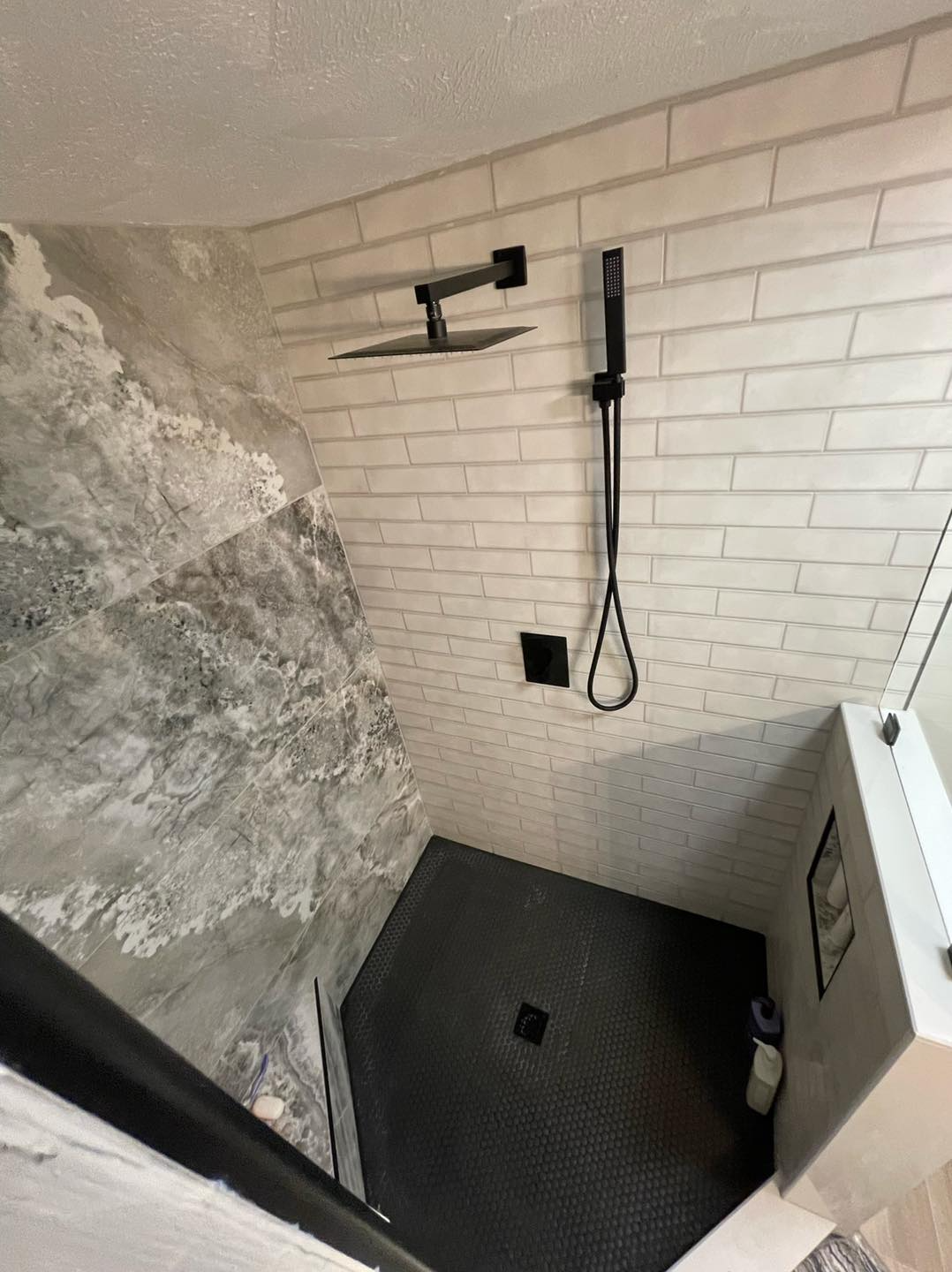 A bathroom with a walk in shower and a shower head.