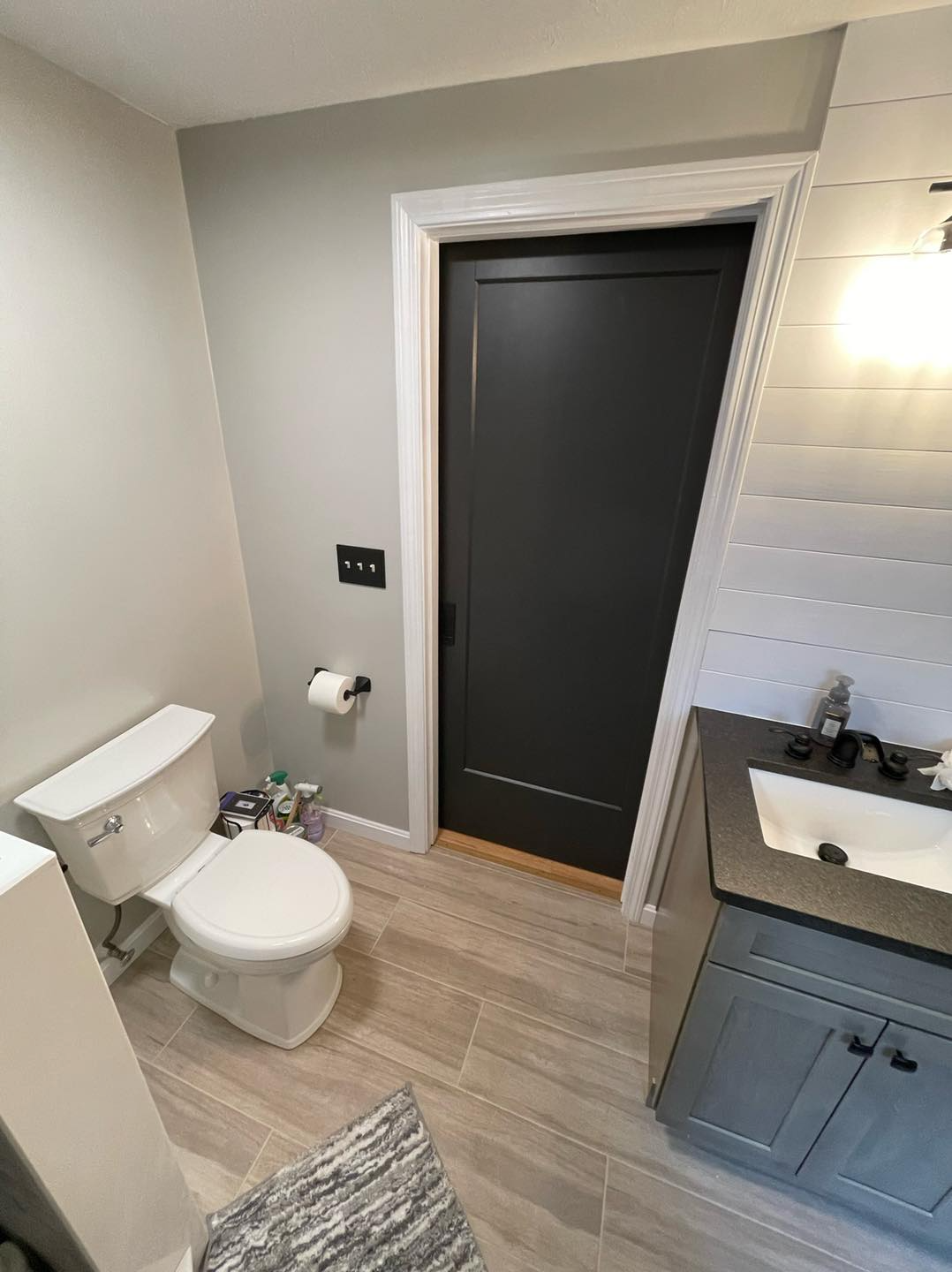 A bathroom with a toilet , sink , and black door.