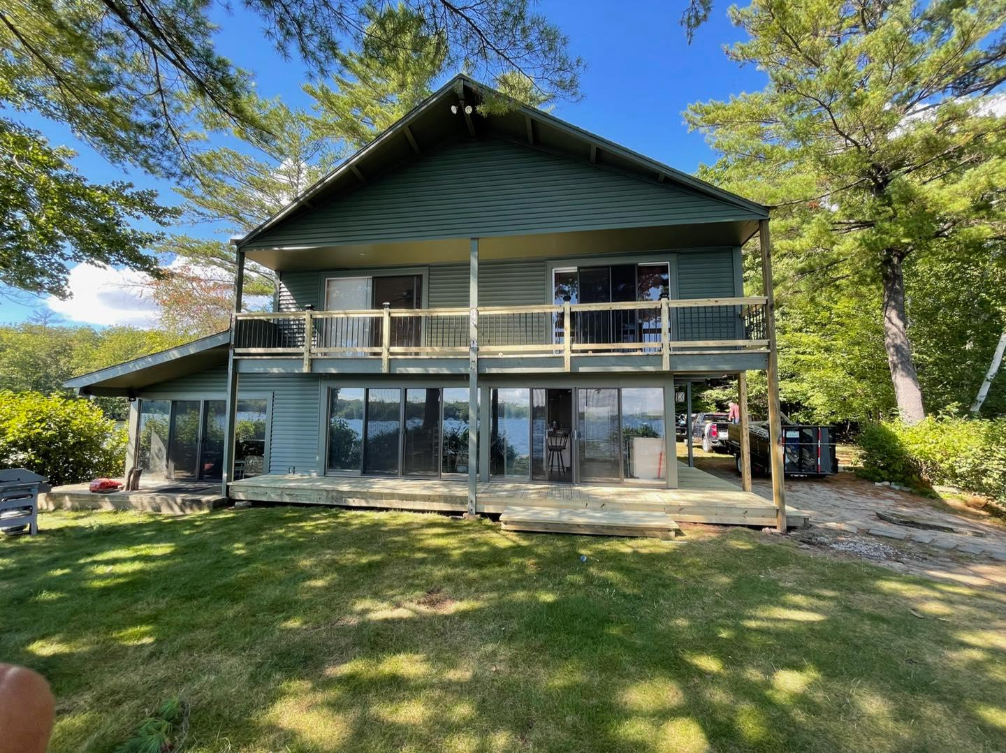 A large house with a lot of windows is sitting on top of a lush green field.