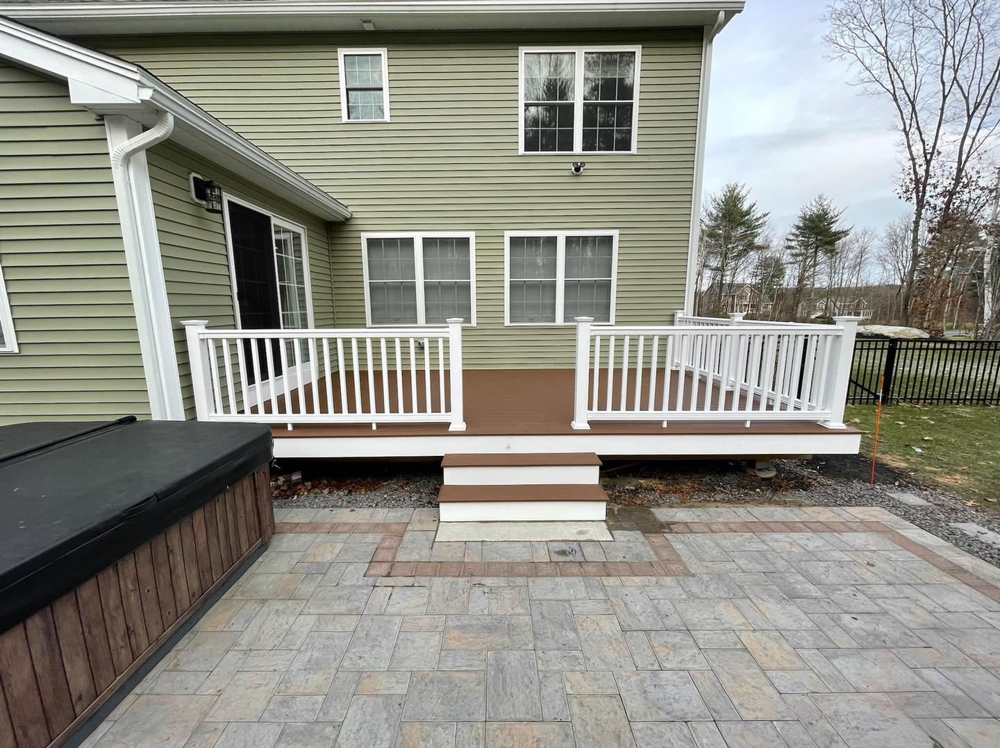 A house with a deck and a hot tub in front of it.