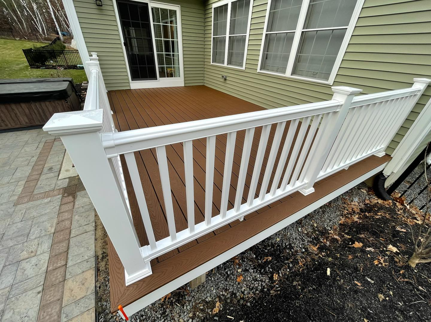 A white railing on a wooden deck next to a house.