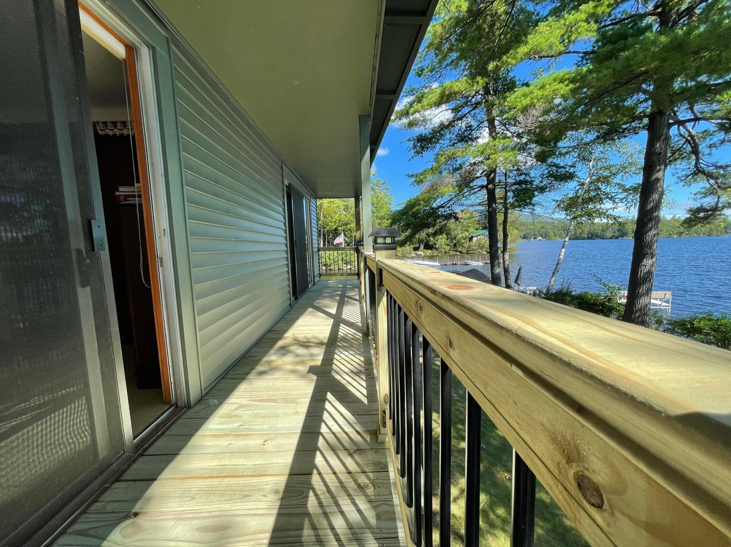 A wooden deck with a view of a lake and trees.