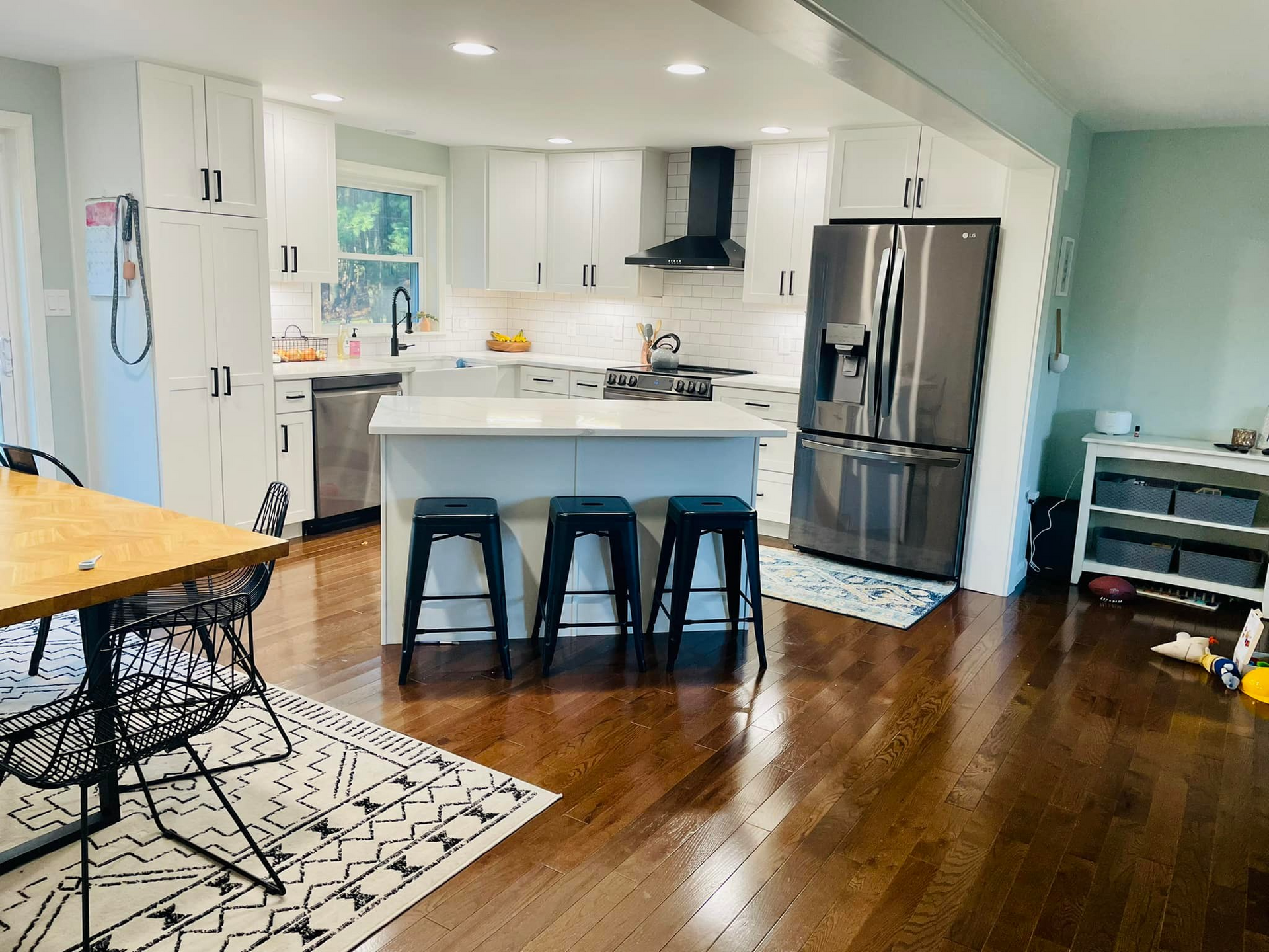 A kitchen with stools , a table , and a refrigerator.