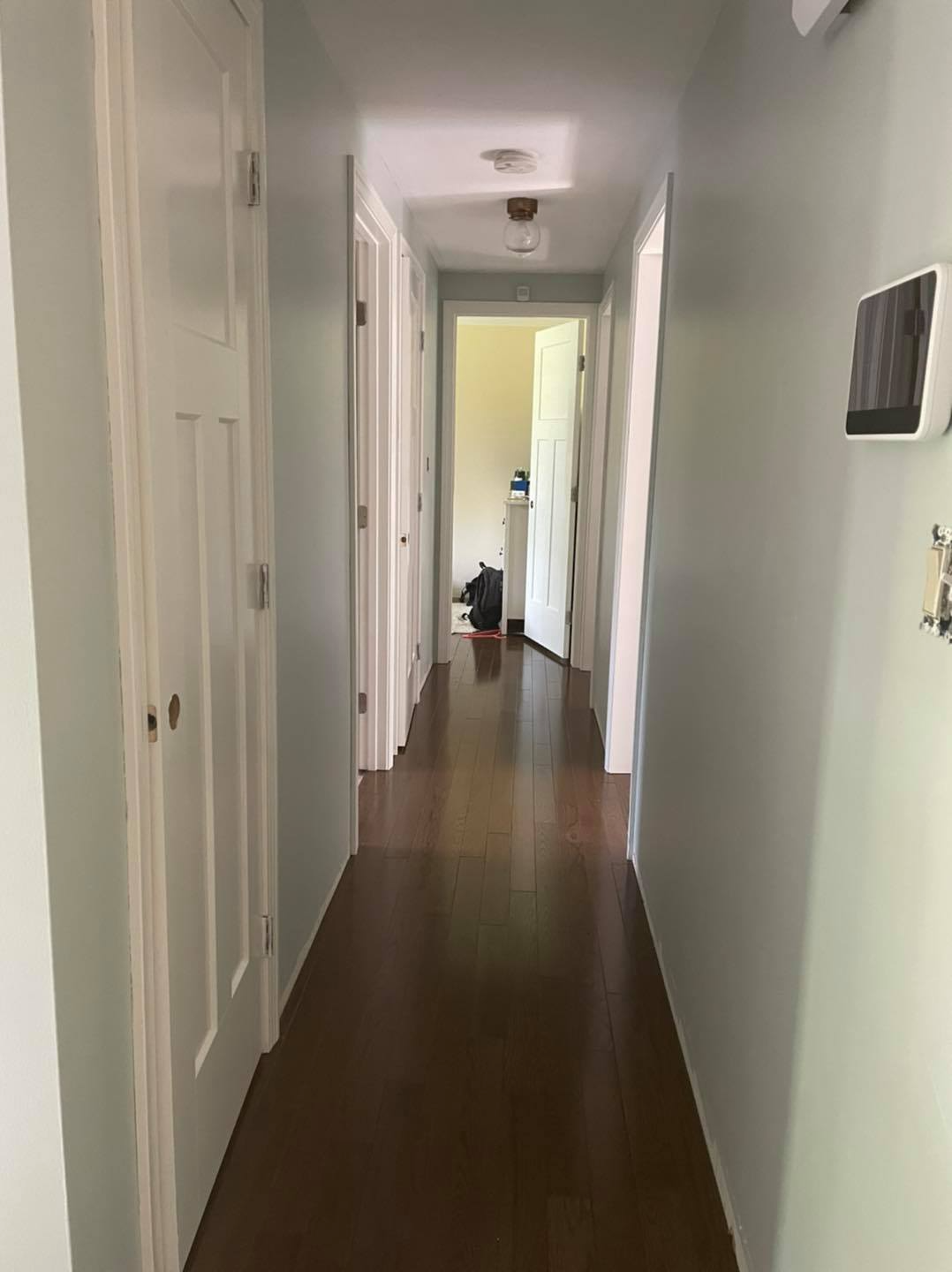 A long hallway with hardwood floors and white walls in a house.