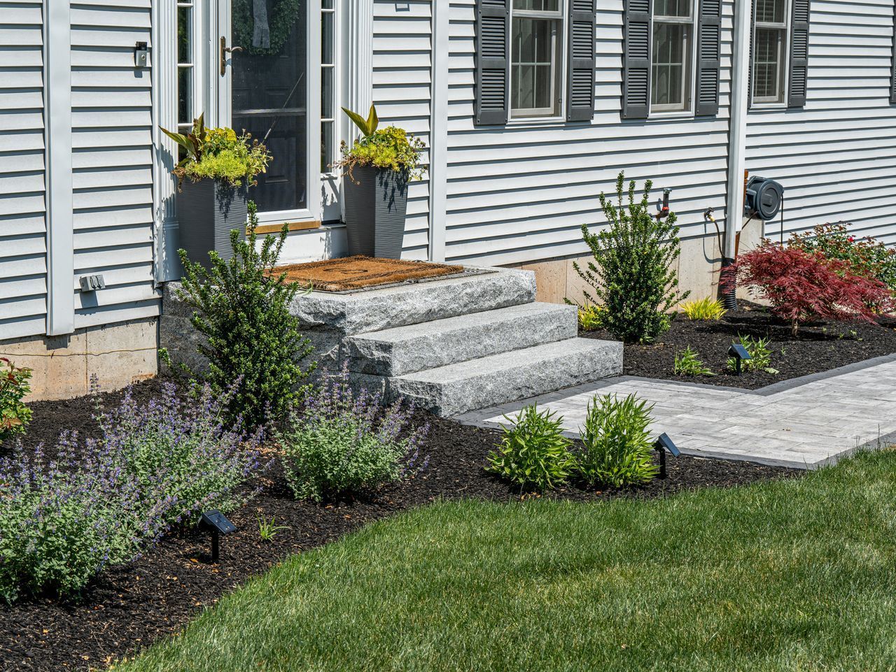 Front yard stone steps leading to a house entrance with landscaping and green lawn